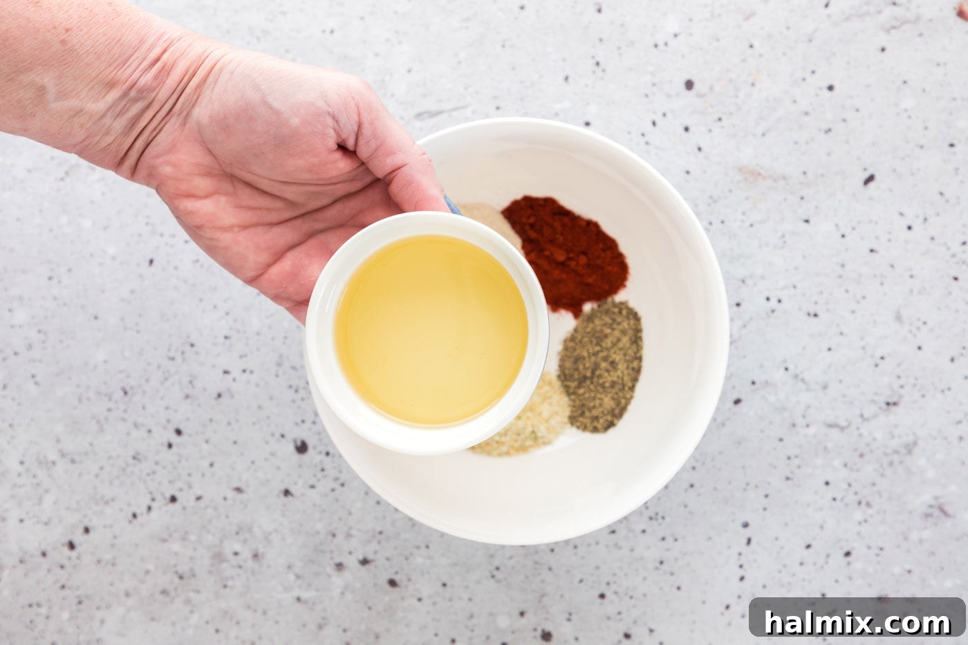Crispy Golden Baked Chicken Thighs 6 adding olive oil to seasoning mix in a bowl