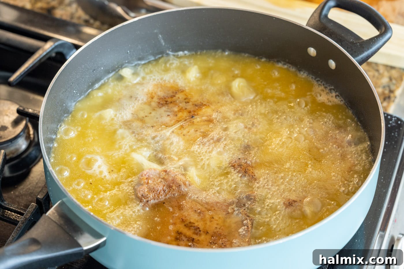 Crispy pork chops frying in a hot skillet, surrounded by bubbling oil