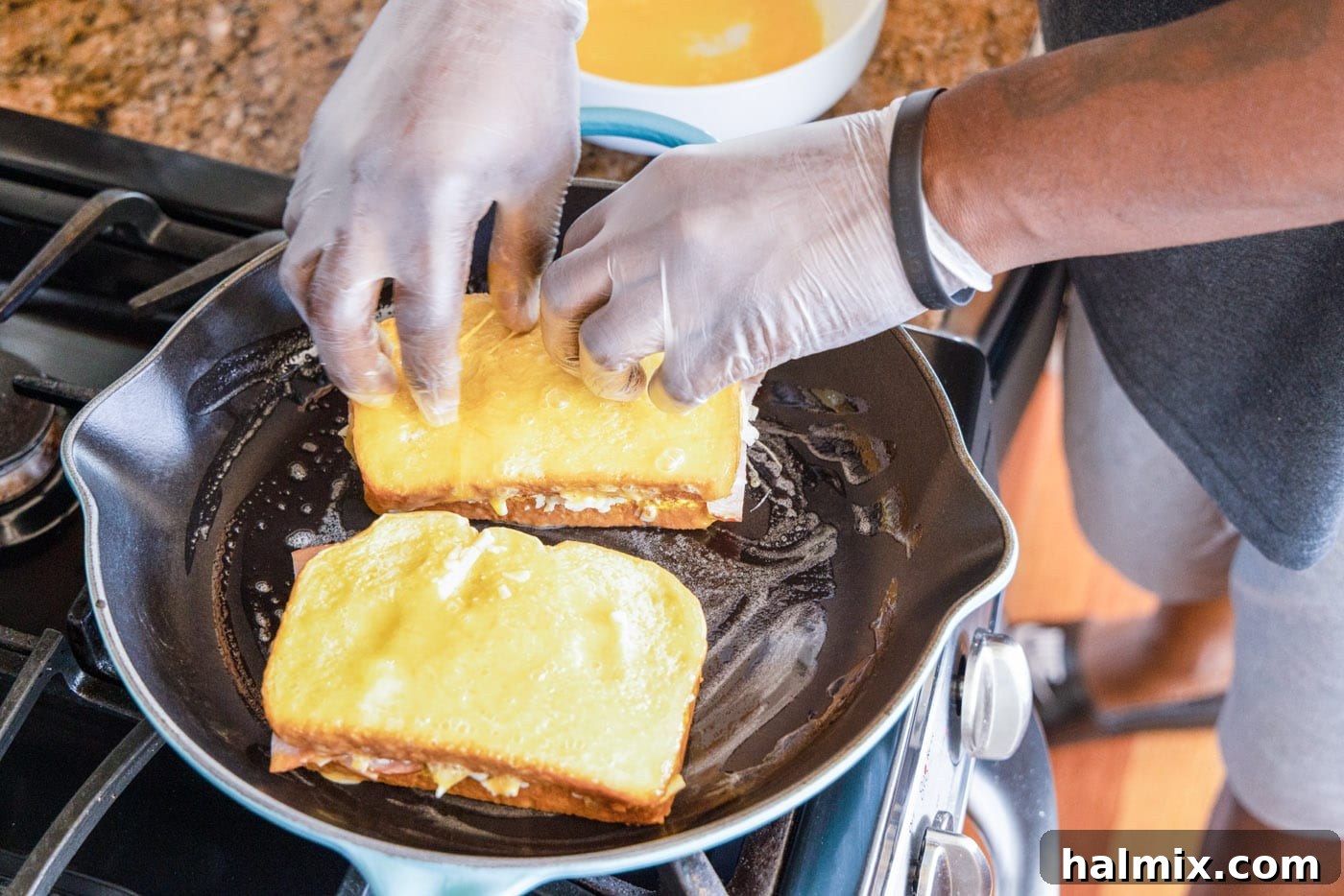 Two Monte Cristo sandwiches frying in a skillet with melted butter, achieving a golden-brown crust.