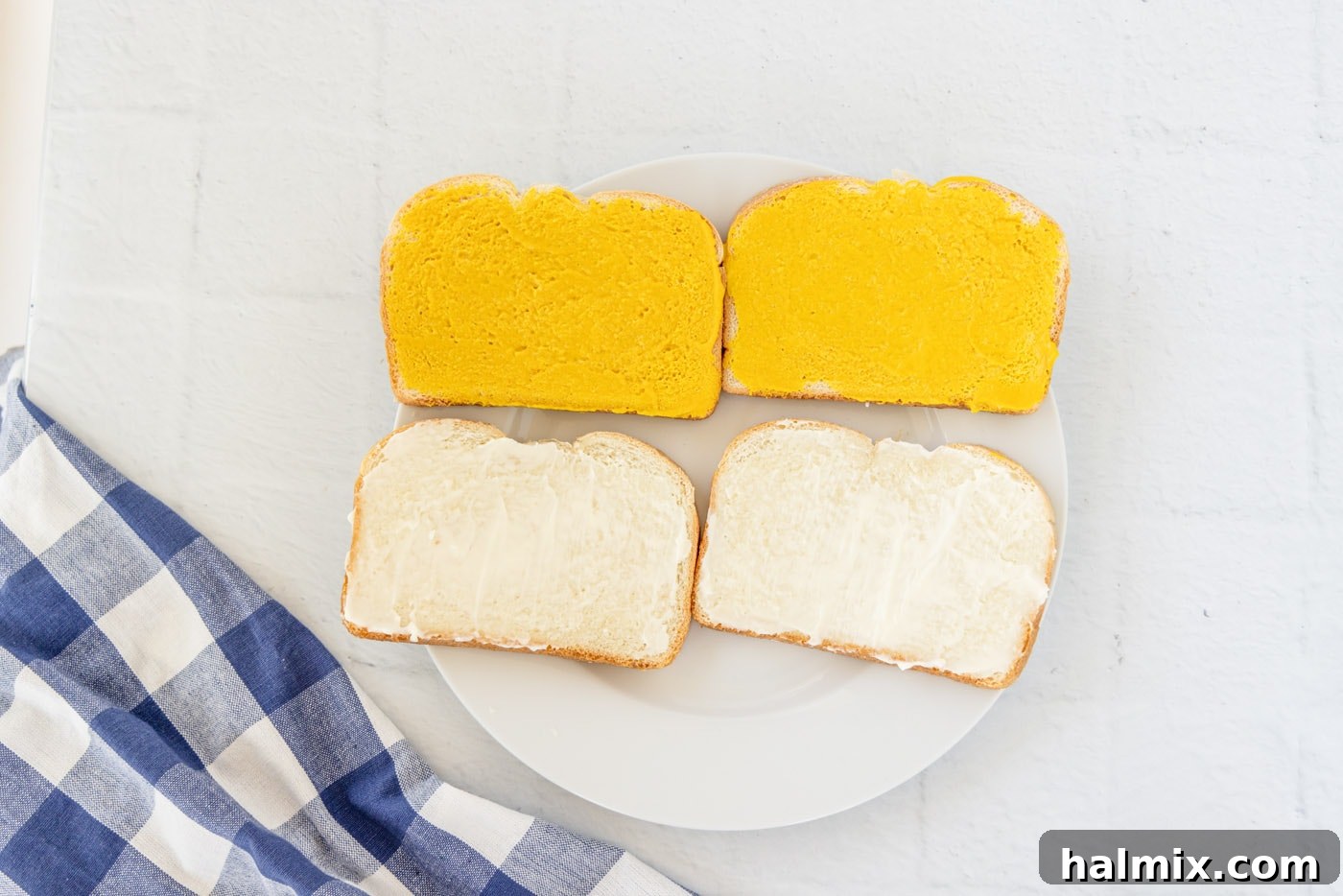 A visual guide showing mayonnaise spread on one slice of sandwich bread and yellow mustard spread on another slice.