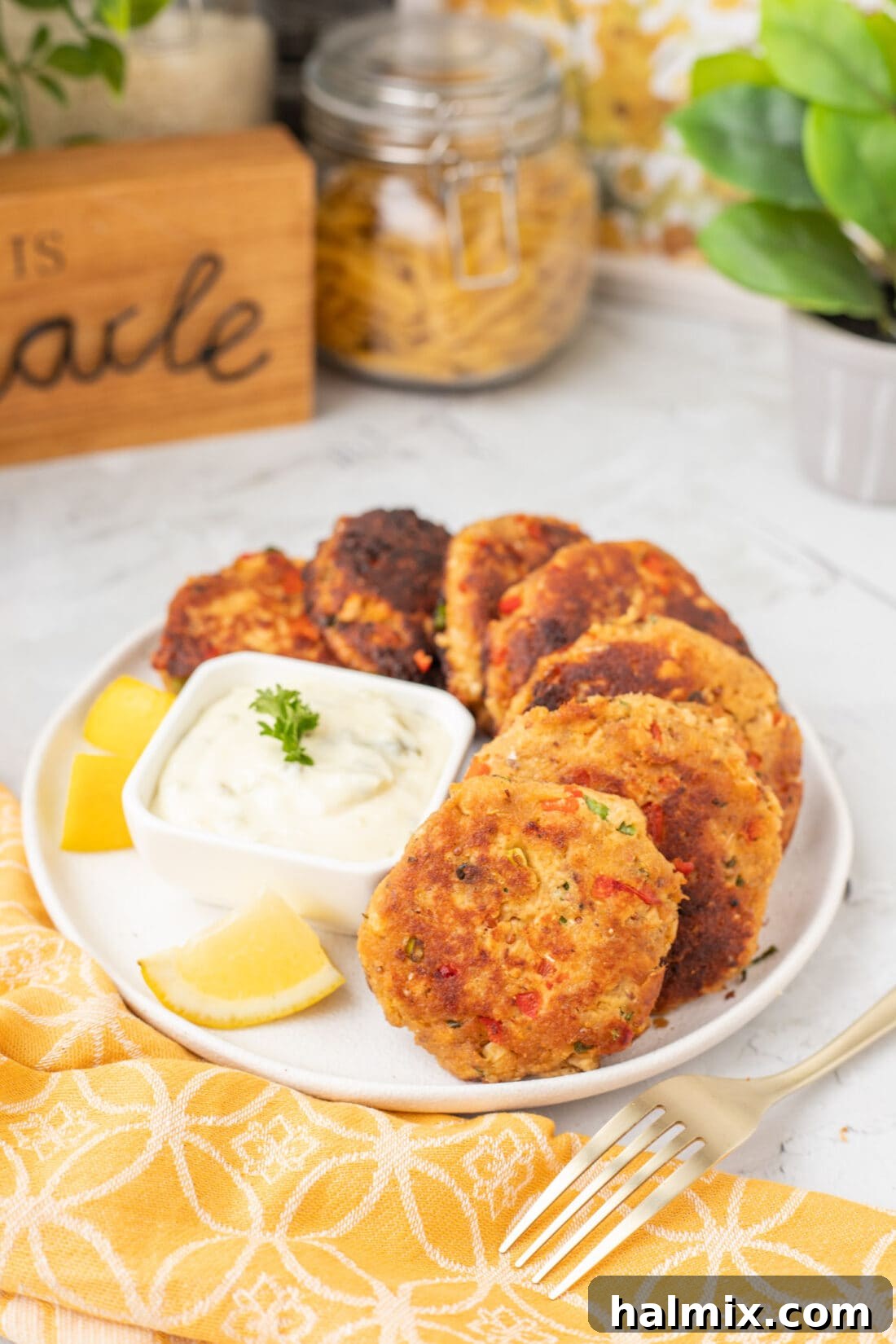 A close-up shot of a salmon croquette on a plate, perfectly golden and drizzled with a creamy white sauce, highlighting its texture and inviting presentation.