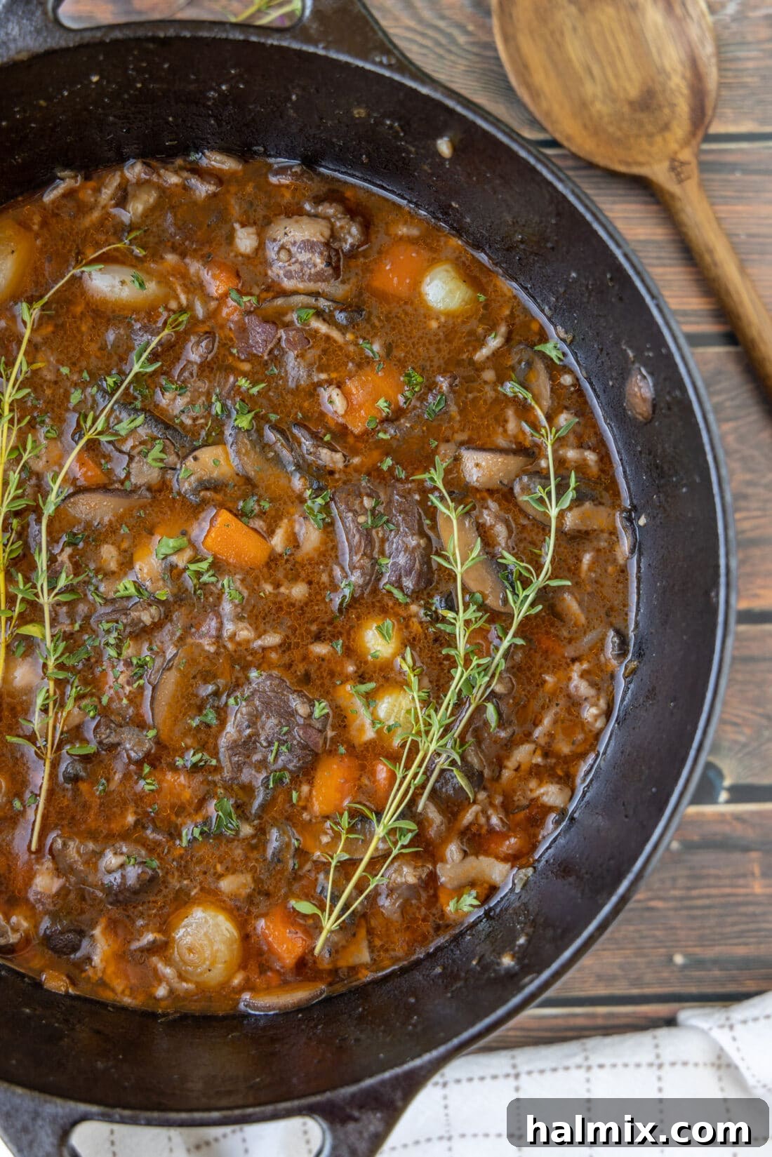Beef Bourguignon in a cast iron dutch oven, garnished with fresh herbs, ready to be served