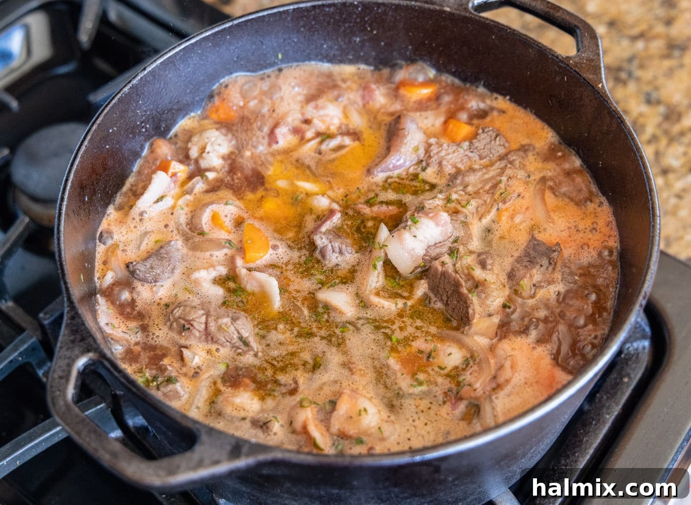 Beef Bourguignon stew simmering in a dutch oven on the stovetop before going into the oven