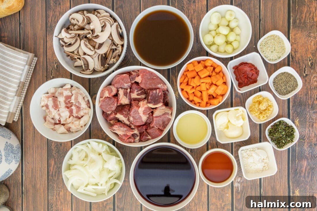 a flat lay of fresh ingredients for Beef Bourguignon, including beef chuck, bacon, onions, carrots, mushrooms, garlic, and herbs