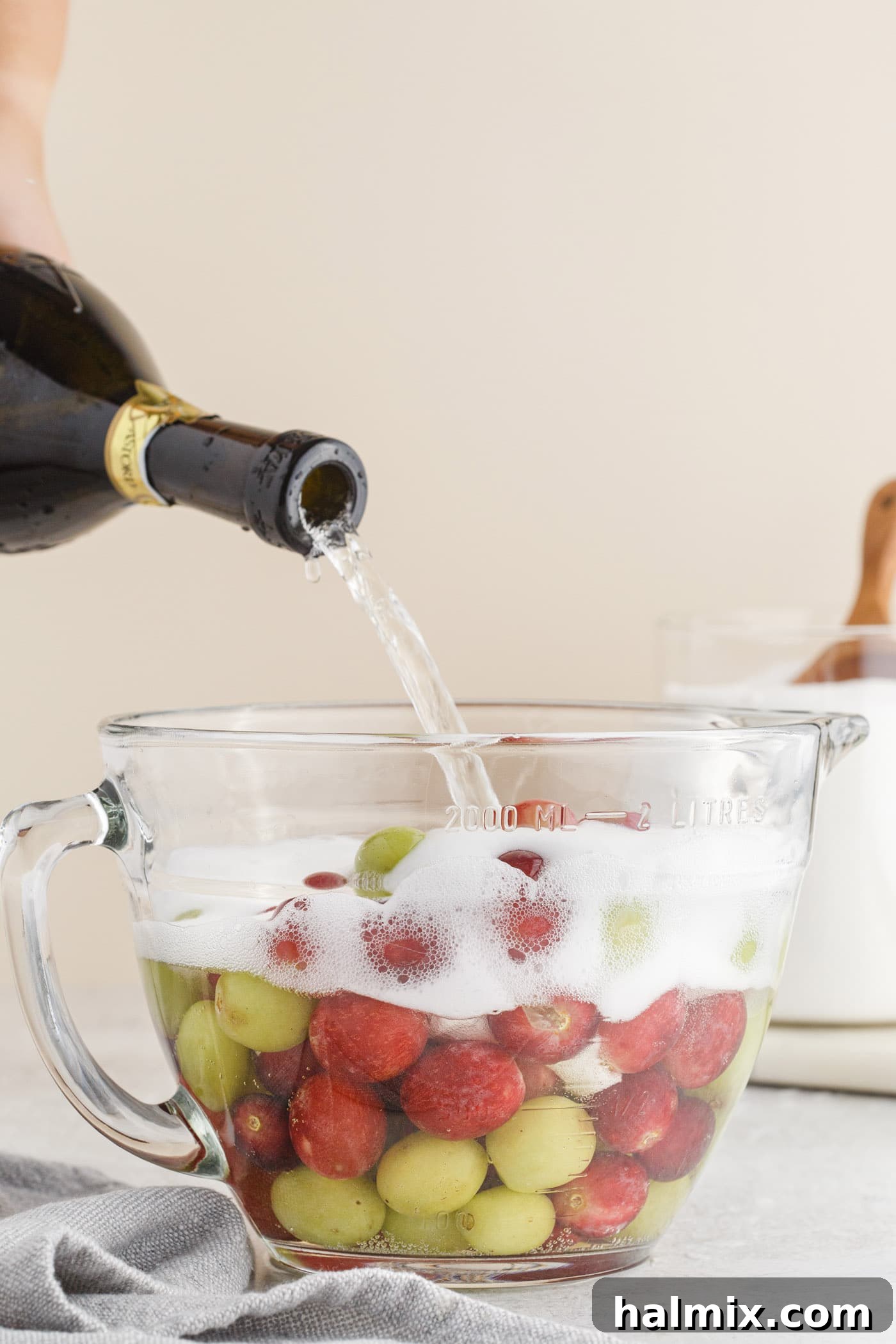 pouring prosecco into a bowl of grapes