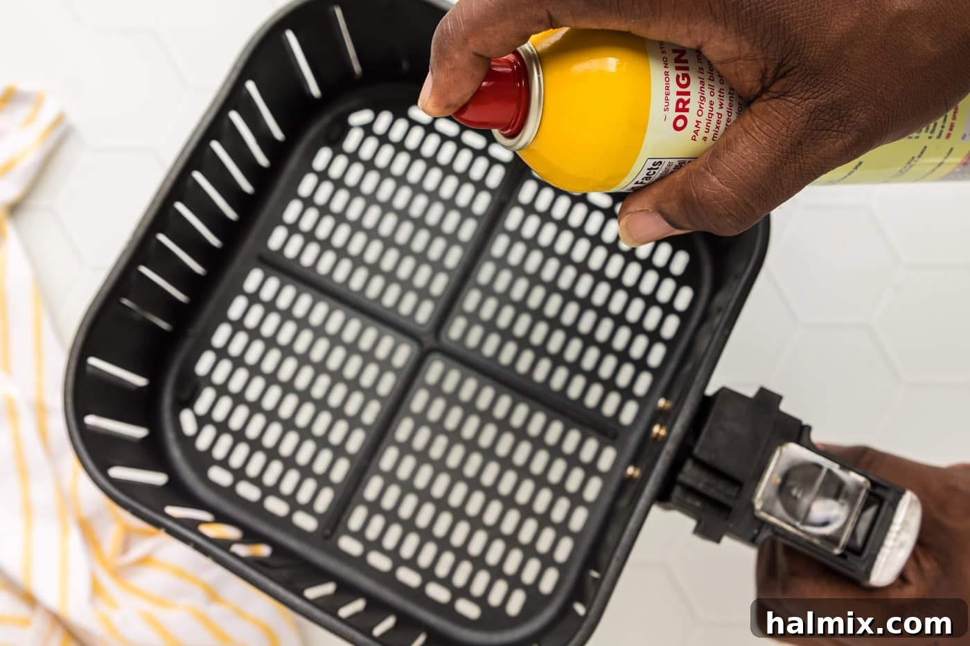 Spraying air fryer basket with cooking spray for non-stick cooking
