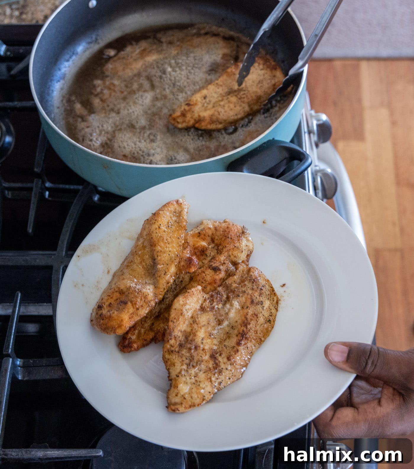 Removing cooked chicken breasts to a plate.