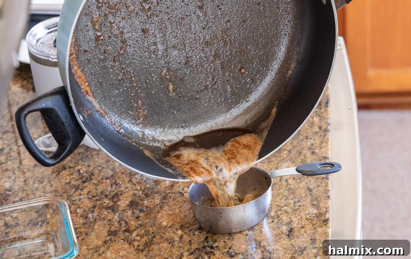 Draining excess oil and butter mixture from the skillet.