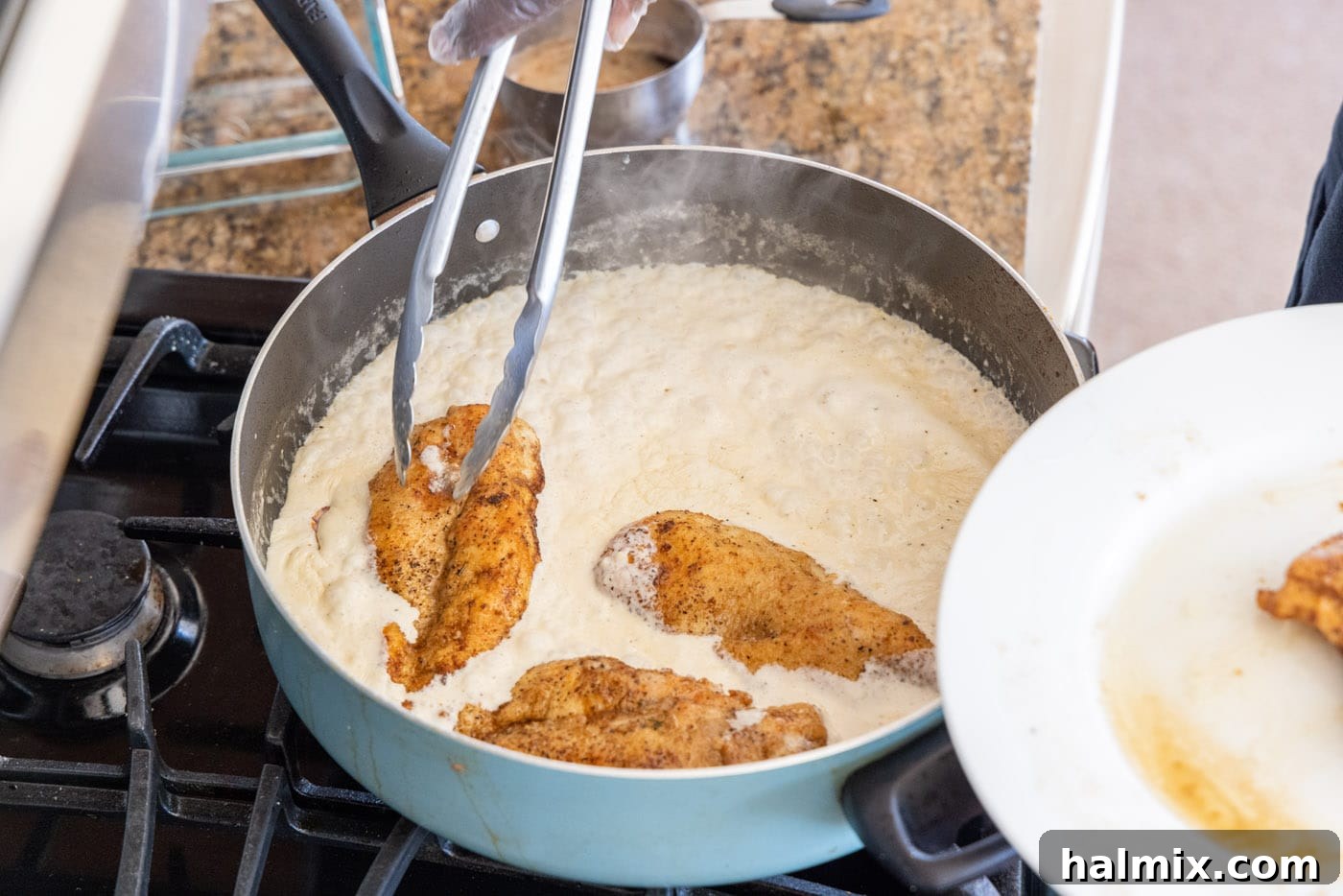 Dredging chicken breasts in heavy cream mixture.