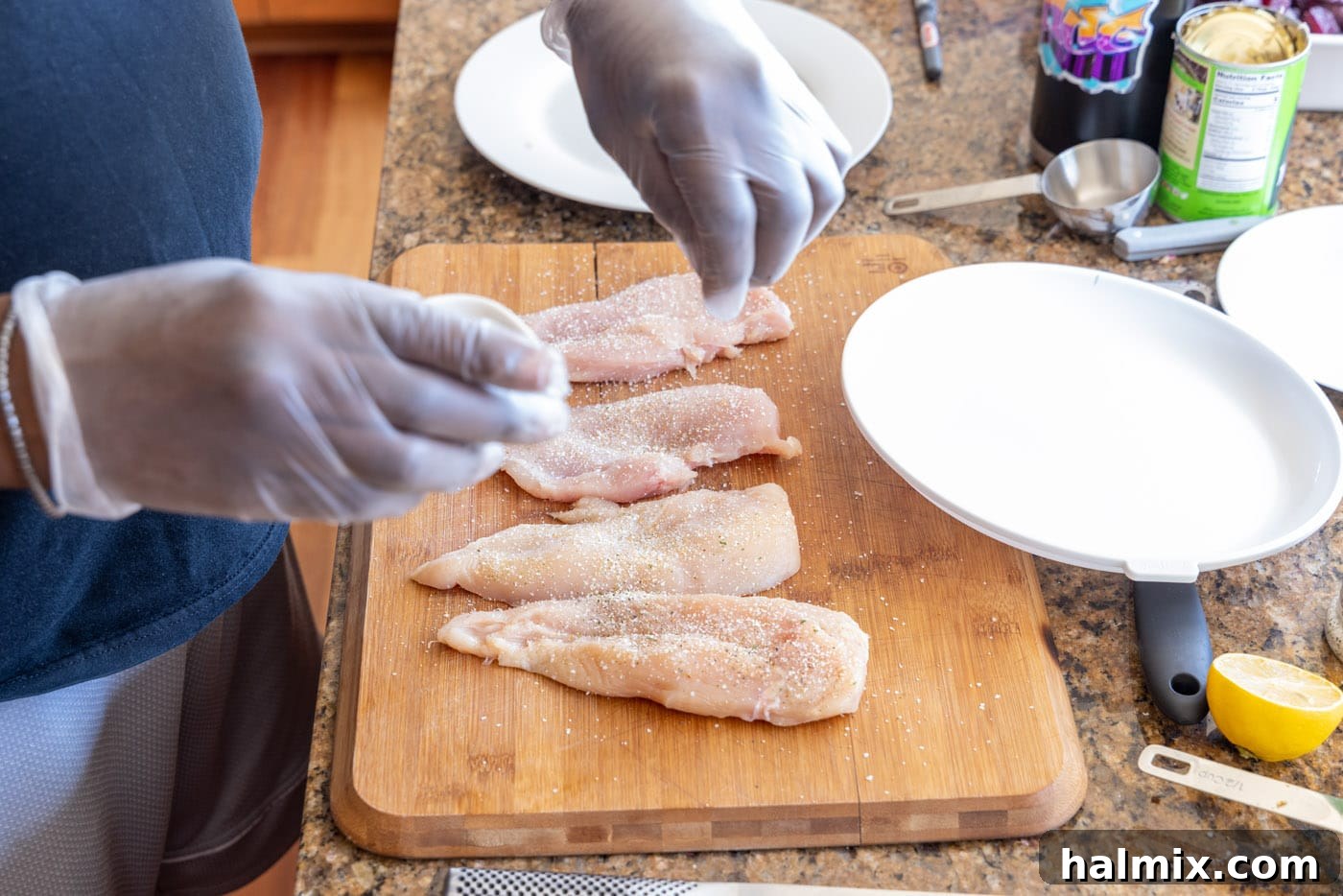 Seasoning chicken cutlets with garlic salt and black pepper.