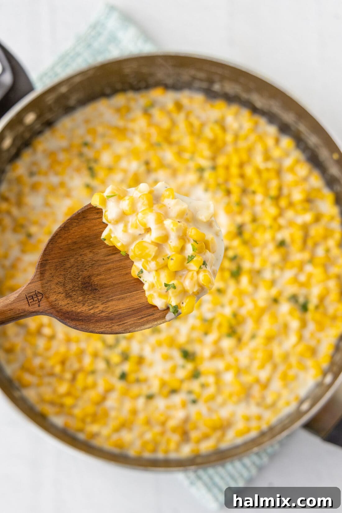 A close-up of a spoonful of creamy homemade creamed corn, showcasing its smooth texture and golden color.