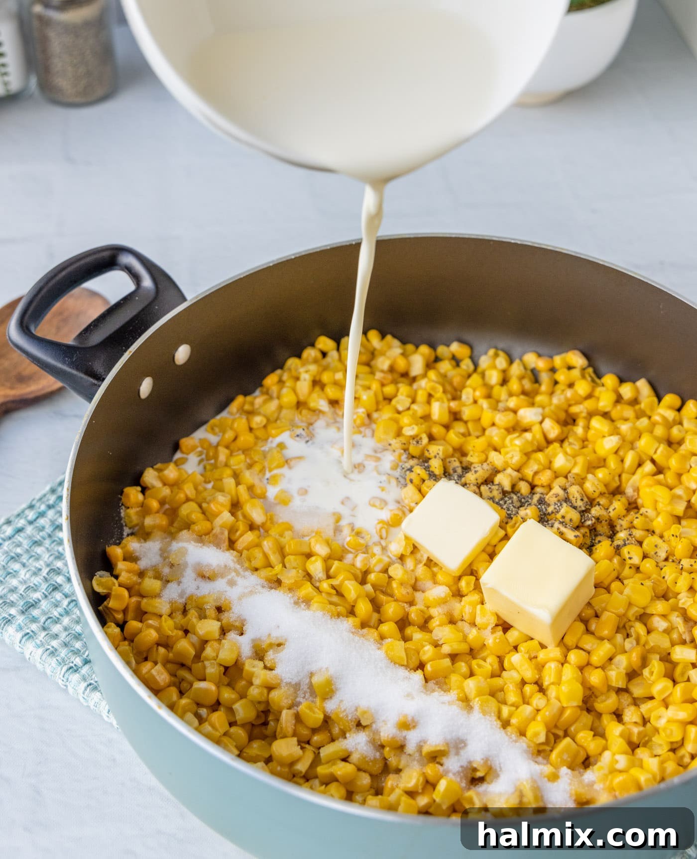 pouring heavy cream into a saucepan with corn mixture