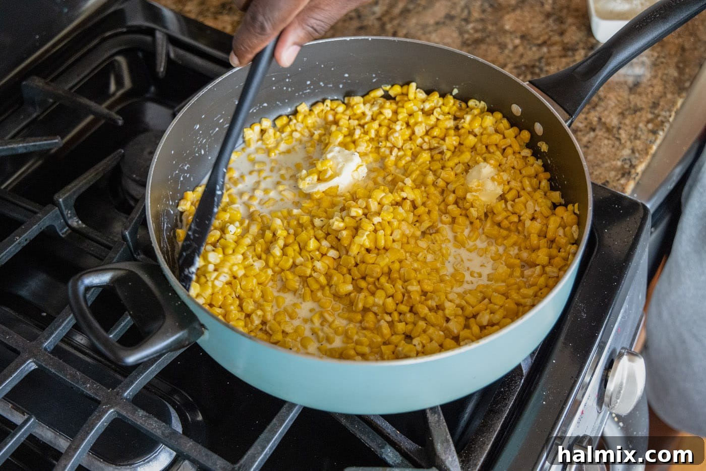 mixing creamy corn in a skillet, showing the simmering process