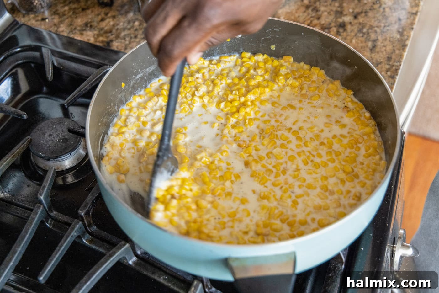 stirring creamed corn in a skillet after adding the thickening agent