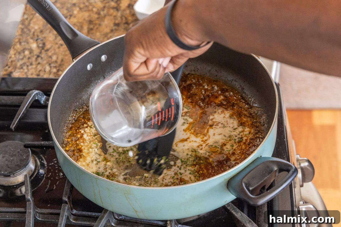 Pouring fresh lemon juice into the skillet with garlic and rosemary, deglazing the pan.