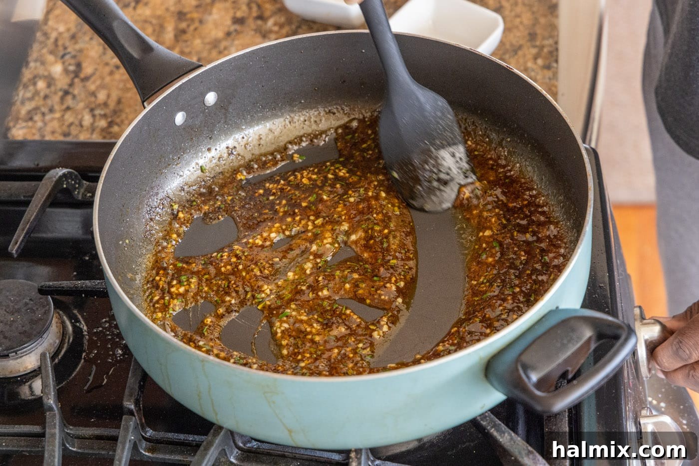 Stirring the pan sauce with rosemary and lemon juice after adding a cornstarch slurry to thicken.