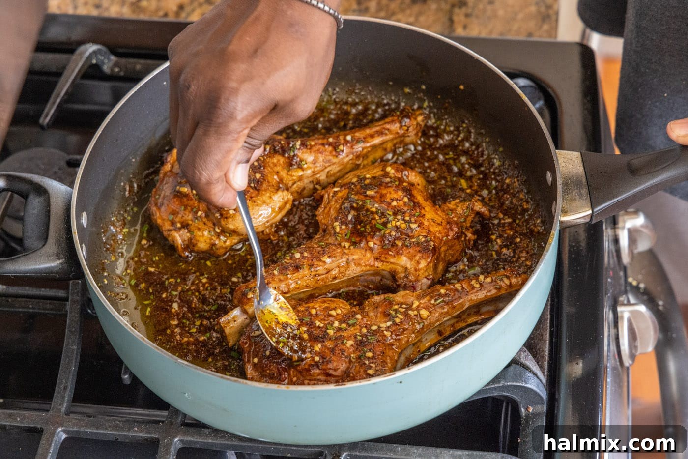 Coating the pan-seared veal chops in the rich rosemary and lemon sauce within the skillet.