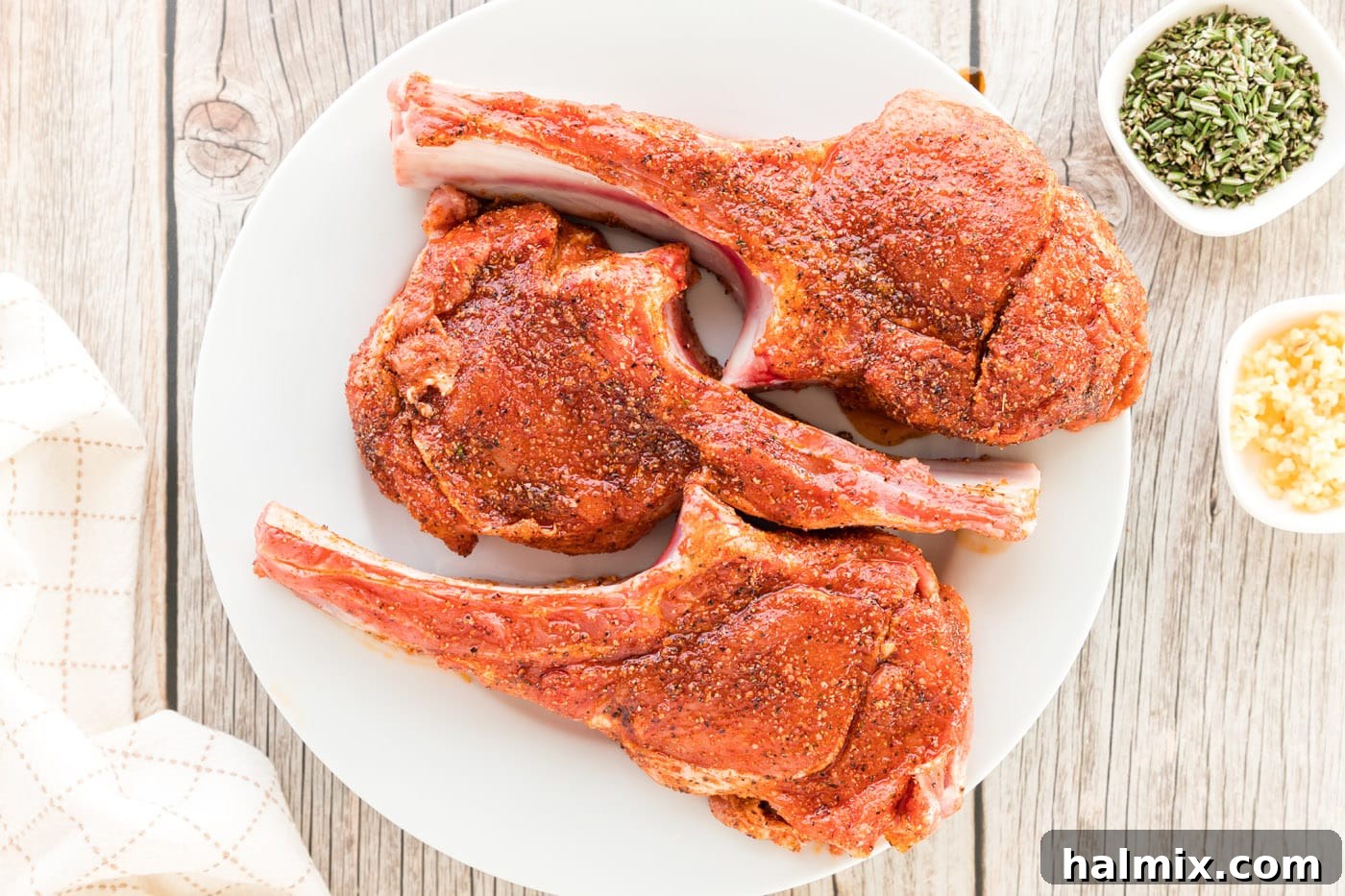 Veal chops coated thoroughly with a savory spice rub on both sides, ready for searing.
