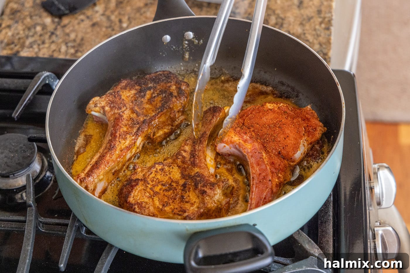 Flipping veal chops in a skillet to ensure even searing and crust development on all sides.