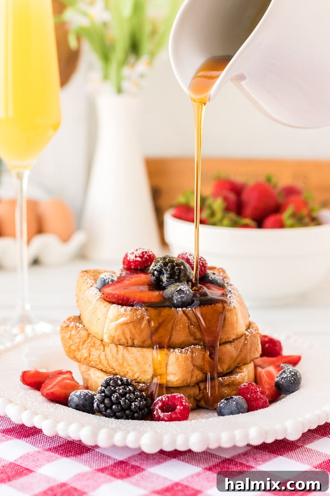 Drizzling maple syrup on freshly made French Toast slices, garnished with berries.