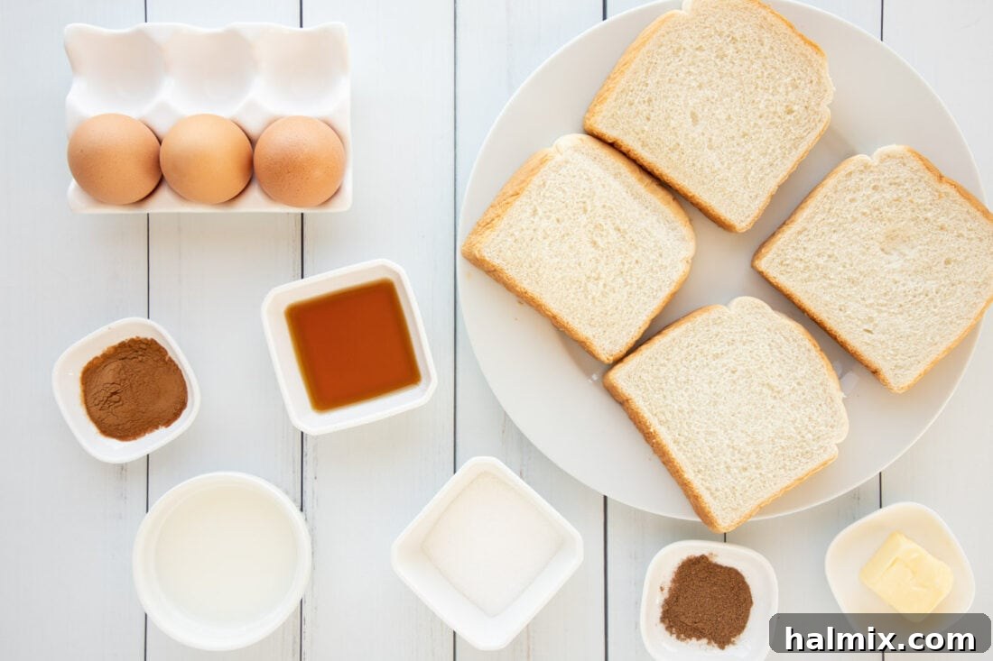 Various ingredients for French Toast laid out on a kitchen counter: bread, eggs, milk, spices, and maple syrup.