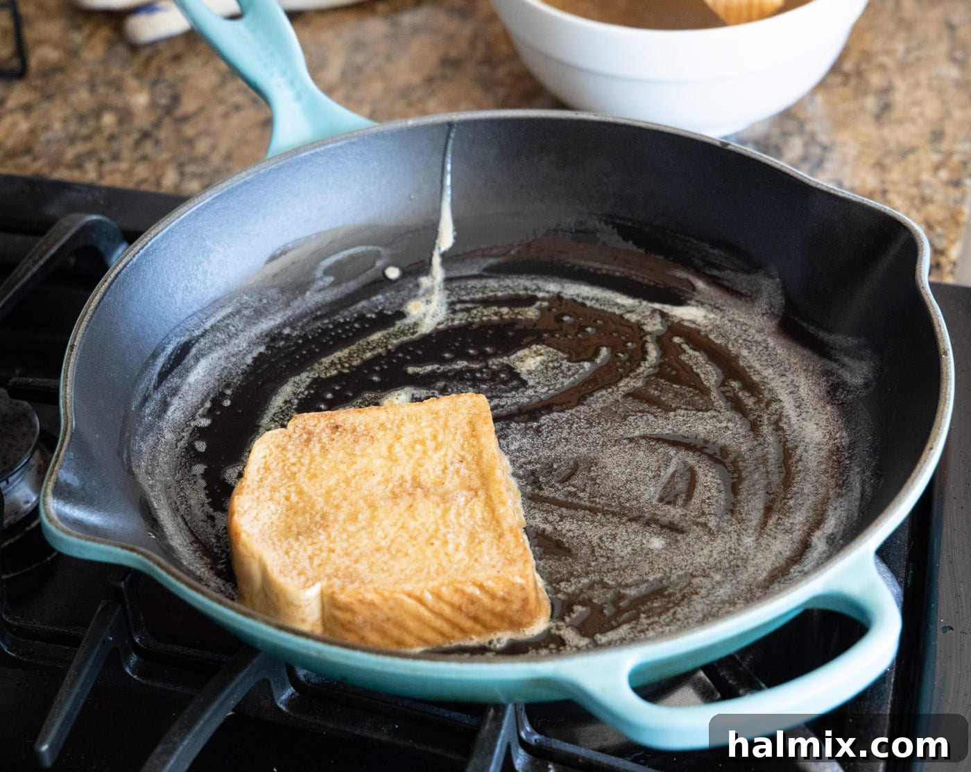 A slice of Texas toast being dipped into the egg and spice mixture.
