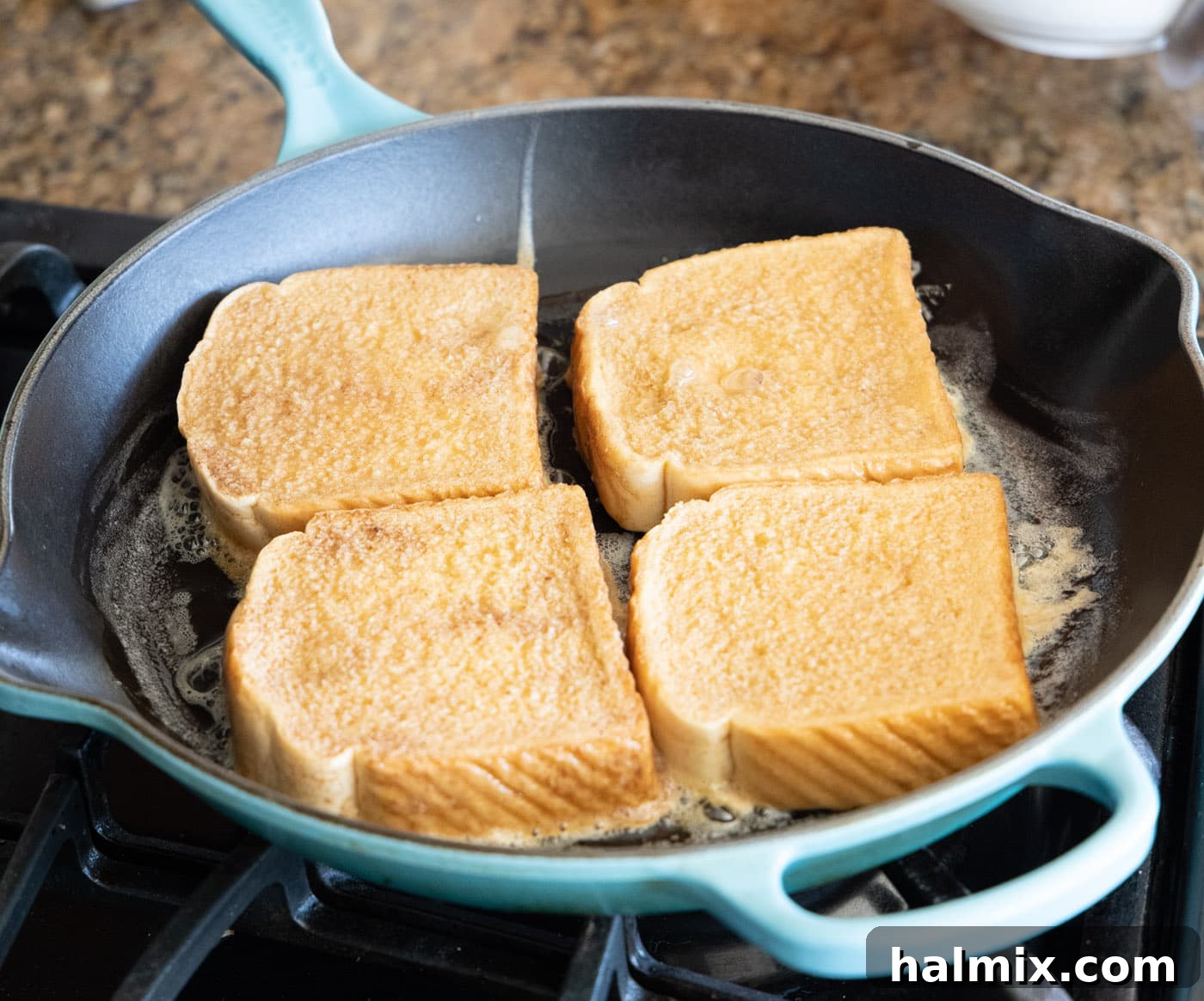 Several slices of French toast cooking in a hot skillet, showing early stages of browning.