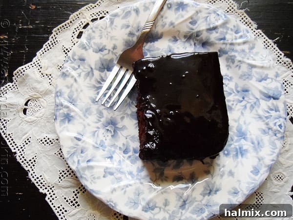 A close-up of a slice of chocolate prune cake, showing its moist texture and rich color, with a delicate caramel glaze.