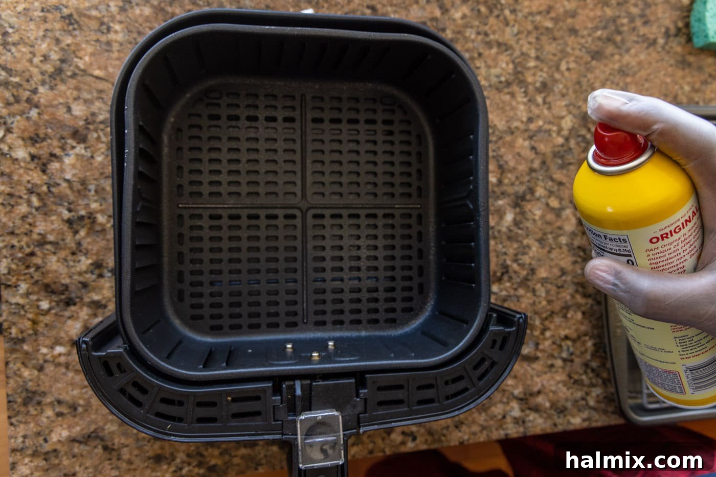 spraying air fryer with cooking spray
