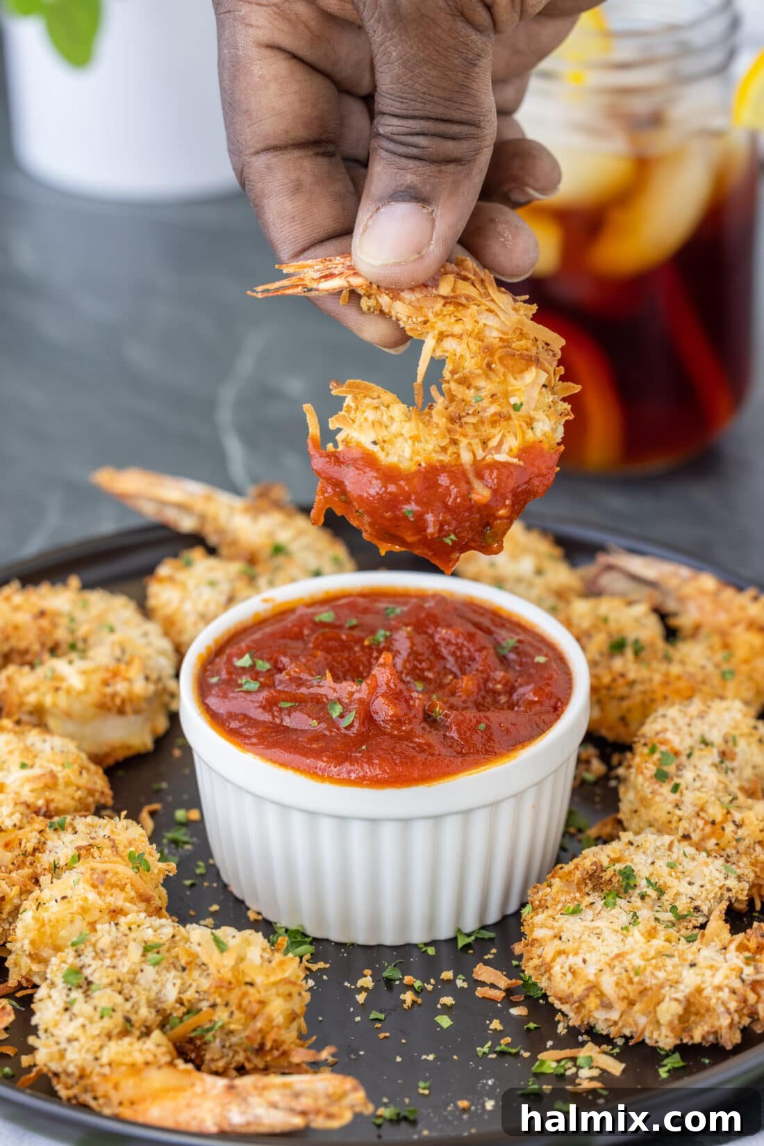 dipping Air Fryer Coconut Shrimp in cocktail sauce
