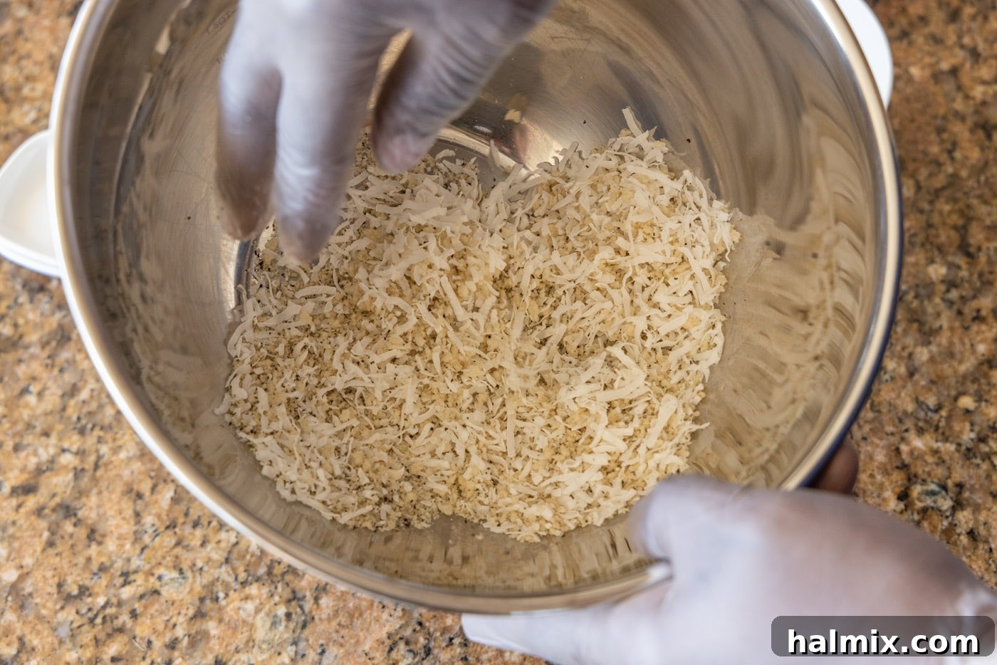 hands tossing coconut with breadcrumbs in a bowl