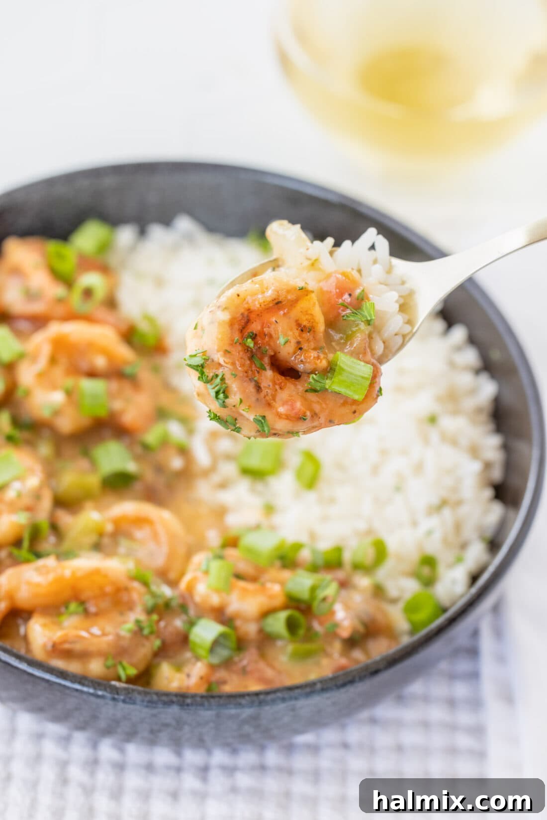 A fork holding a generous portion of Shrimp Etouffee, showcasing the rich sauce and tender shrimp.
