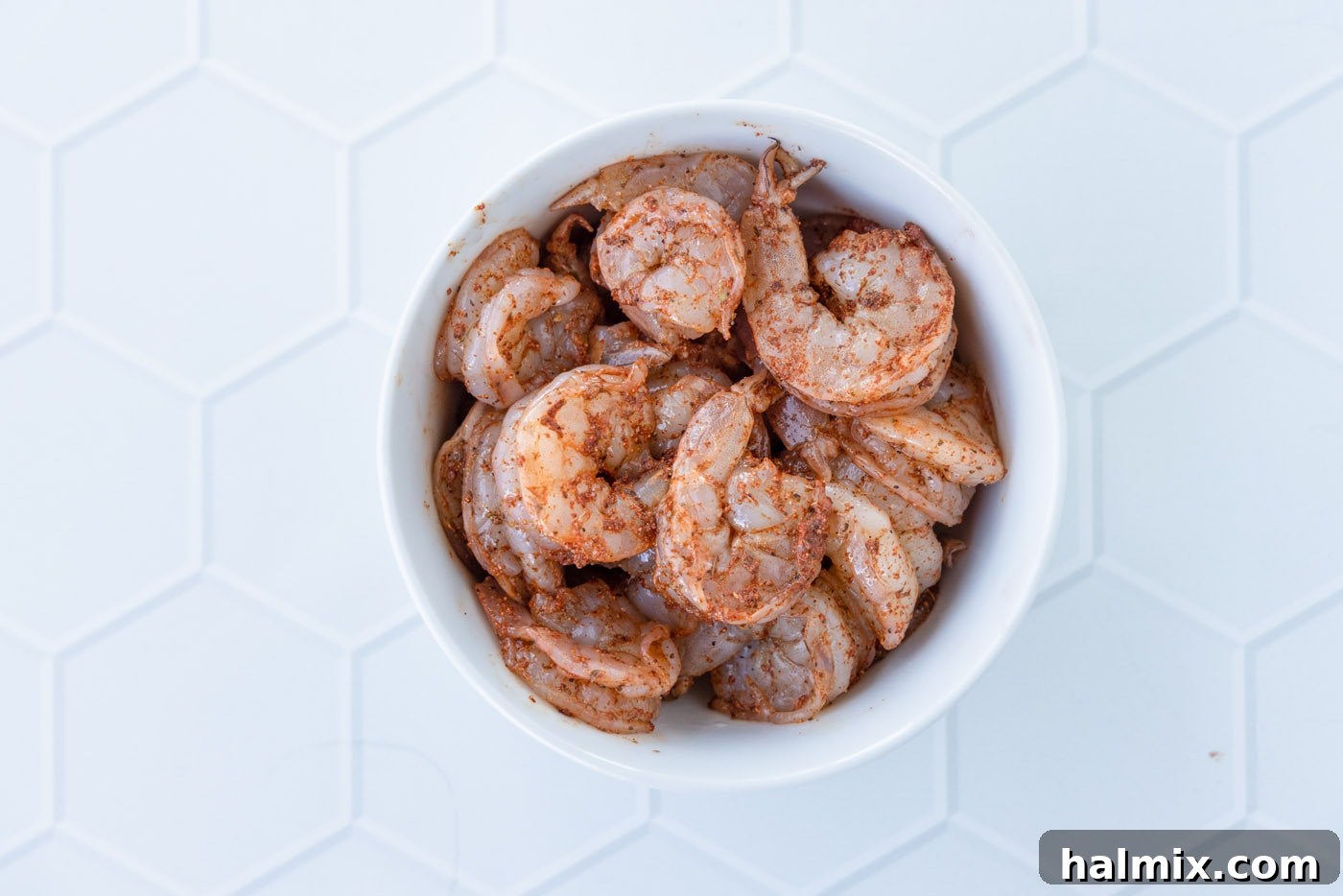 Raw shrimp coated with Cajun seasoning in a bowl, ready for cooking.