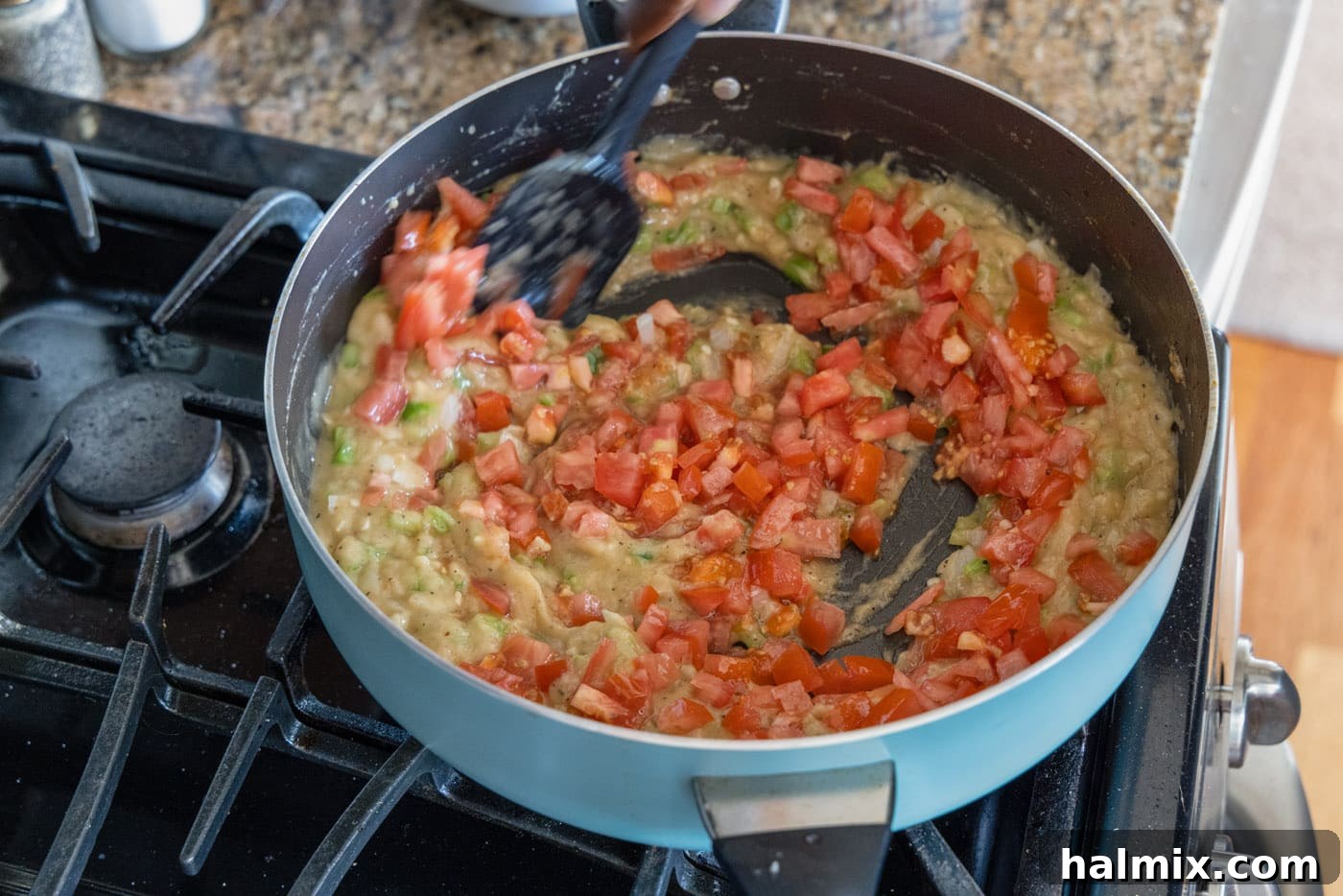 Chopped tomatoes added to the simmering etouffee gravy in a skillet.