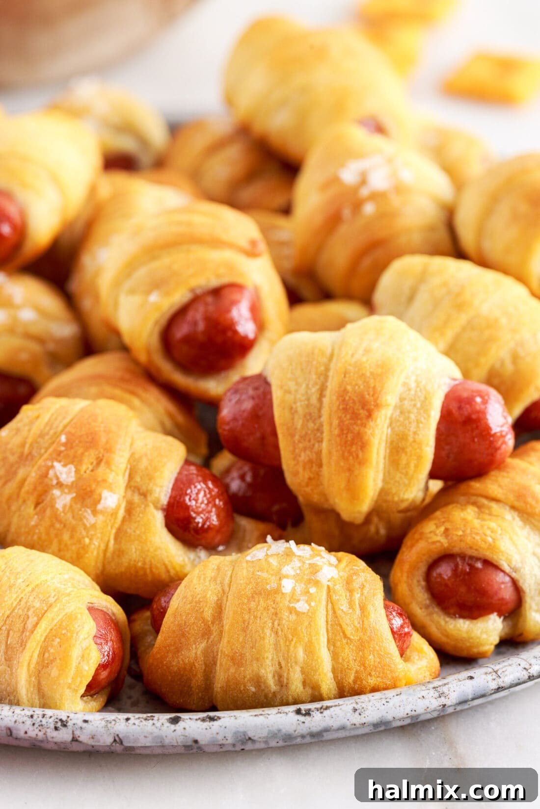 Sausage Swaddles 2 Plate of golden-brown Pigs in a Blanket ready to serve, a perfect party appetizer.