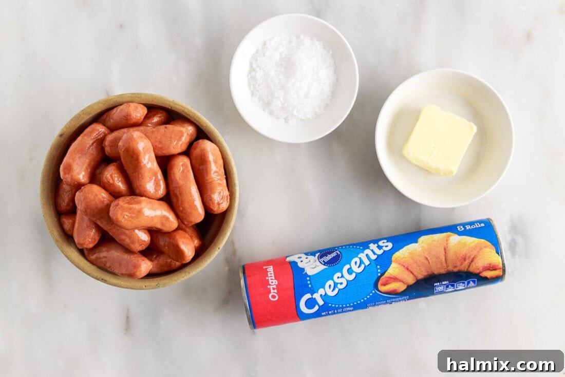Sausage Swaddles 4 Ingredients laid out on a table: crescent rolls, cocktail sausages, butter, and flaked sea salt.