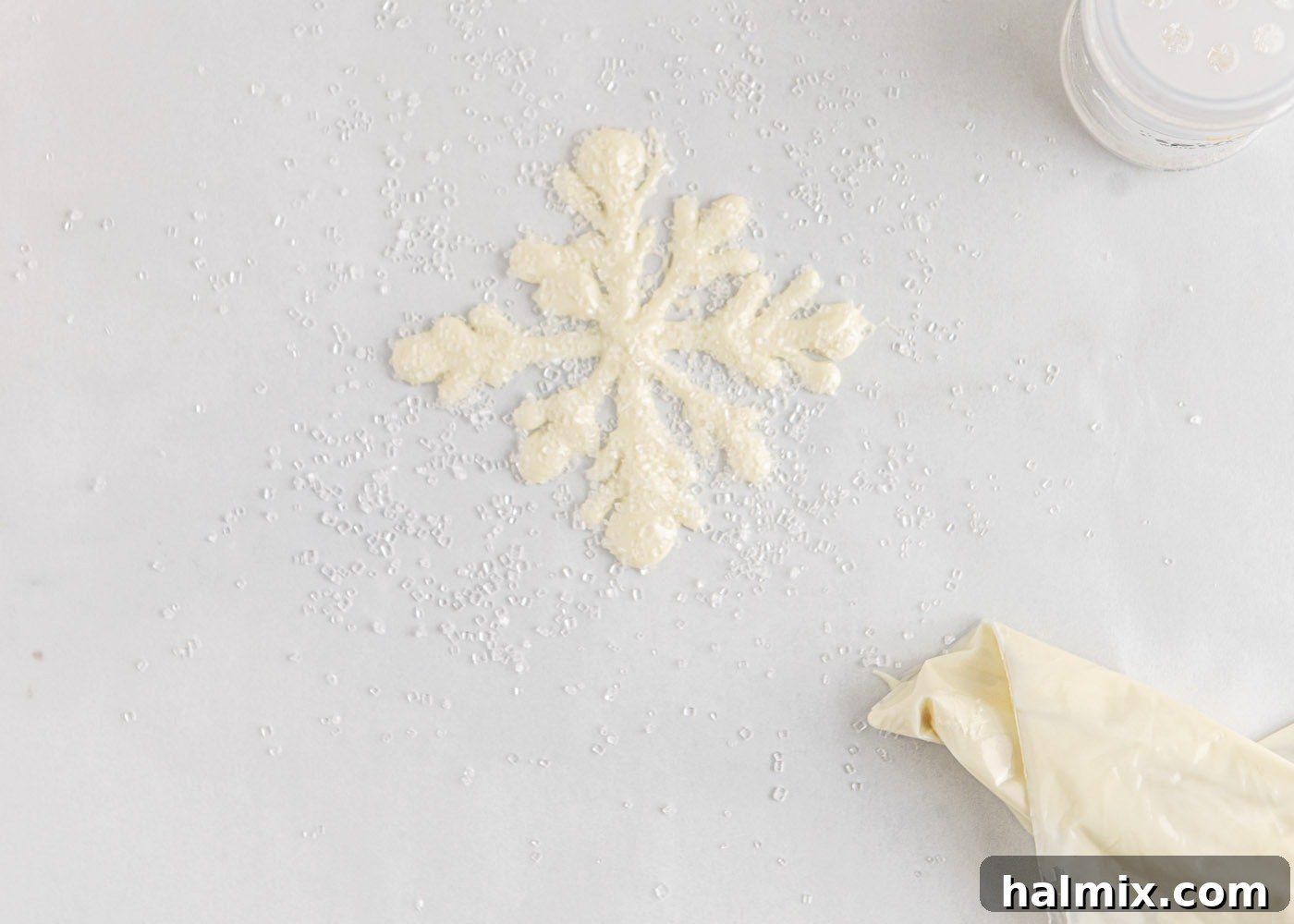 White chocolate snowflakes being sprinkled with sugar crystals