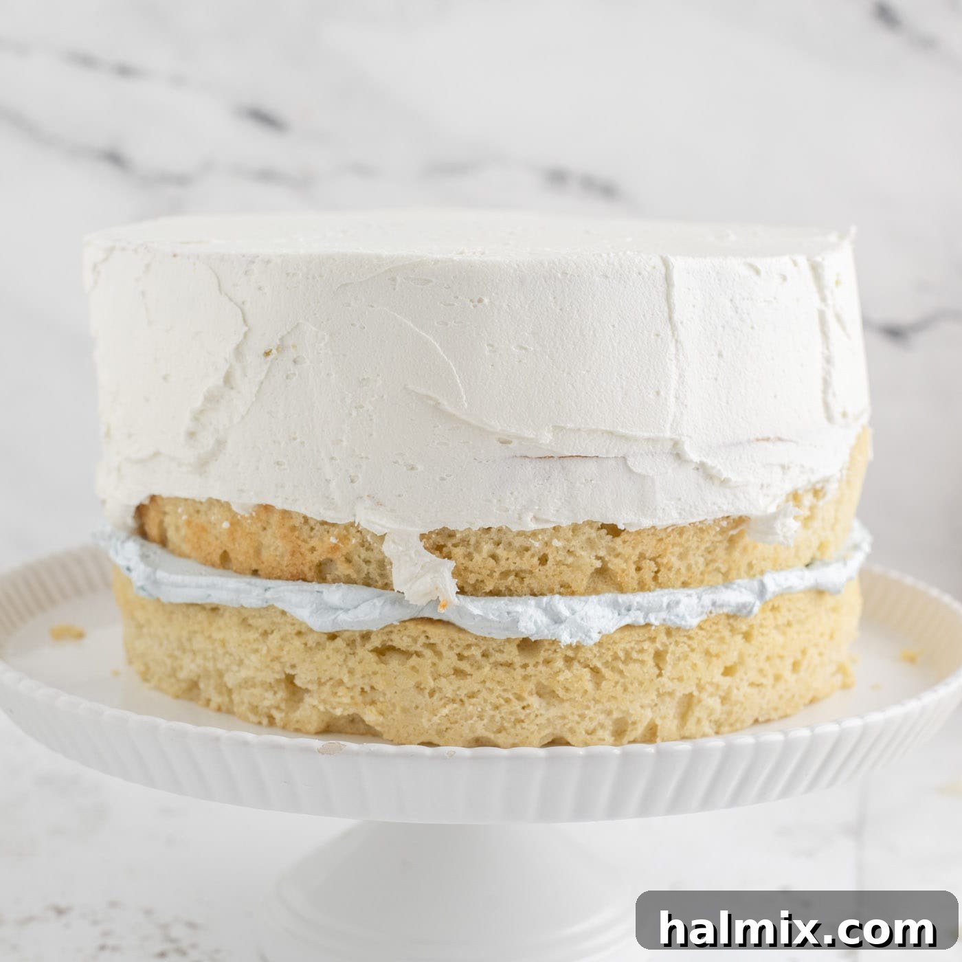 Frosting a tiered cake with white buttercream on top layers