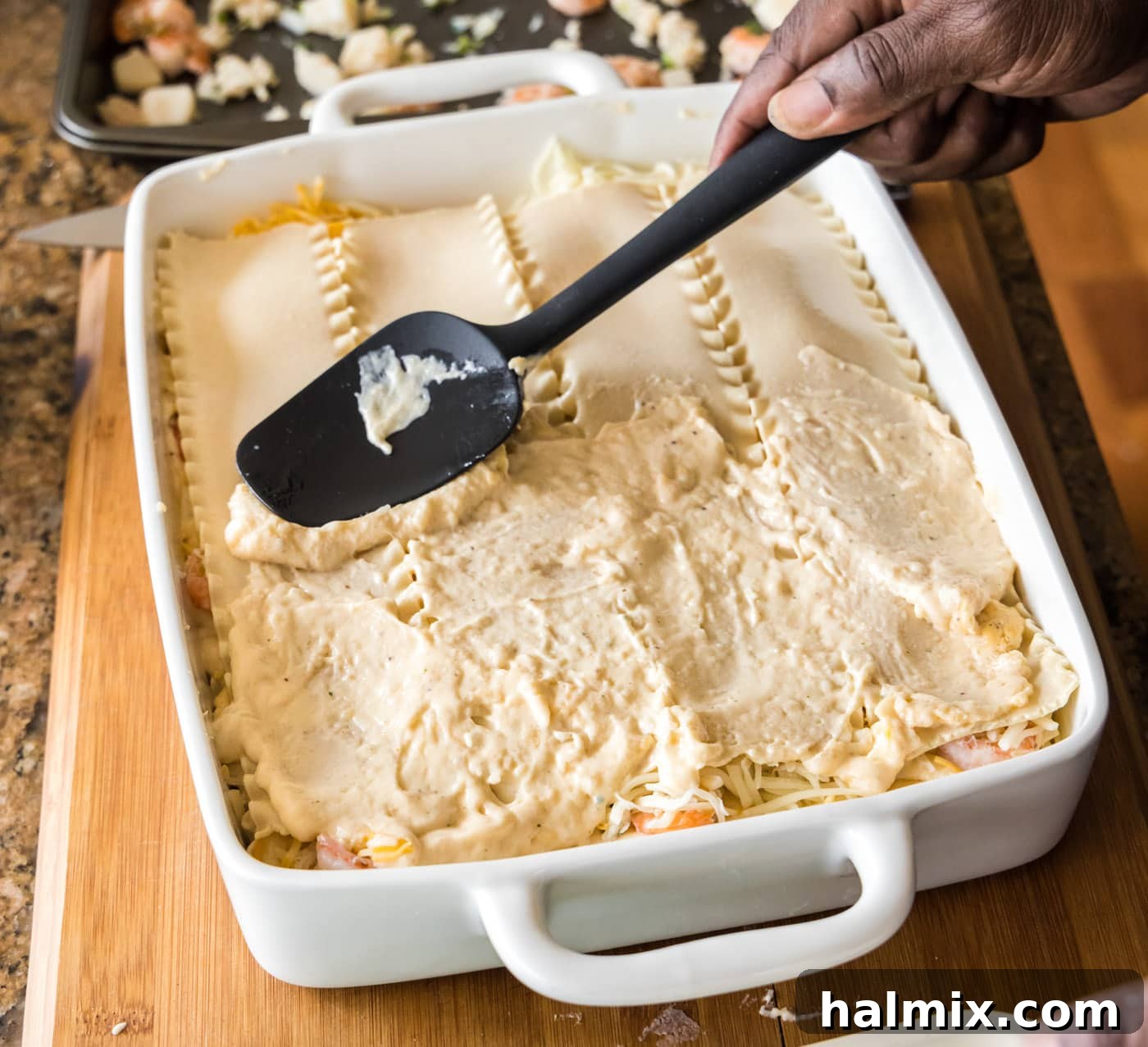 Fisherman's Lasagna 20 Spreading another layer of creamy sauce over the lasagna noodles in the baking dish.