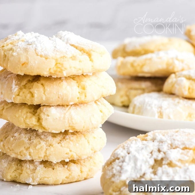 Delicious Orange Crinkle Cookies stacked high, showcasing their soft texture and snowy appearance. A beautifully stacked tower of baked orange crinkle cookies, generously coated in powdered sugar, ready for serving or gifting.
