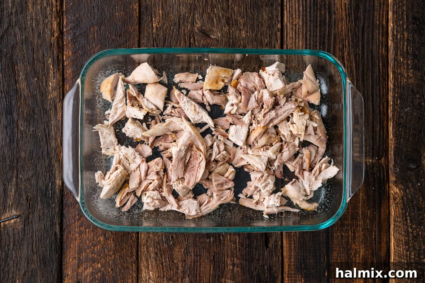 Cooked, shredded chicken spread evenly in a 9x13 inch casserole dish.
