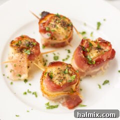 Bacon Wrapped Scallops on a white plate with a side of lemon and parsley.