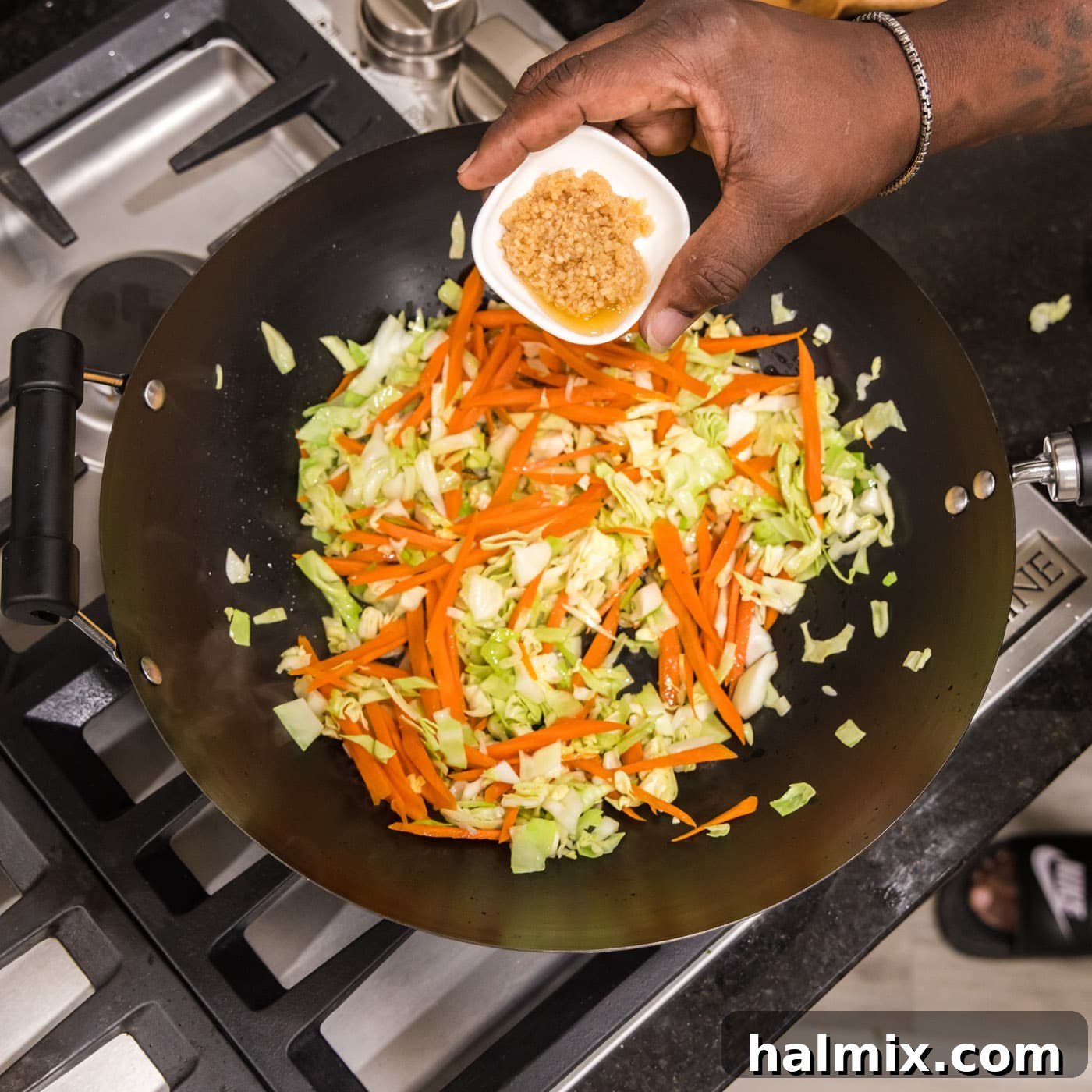 Adding garlic to wok with carrot and cabbage