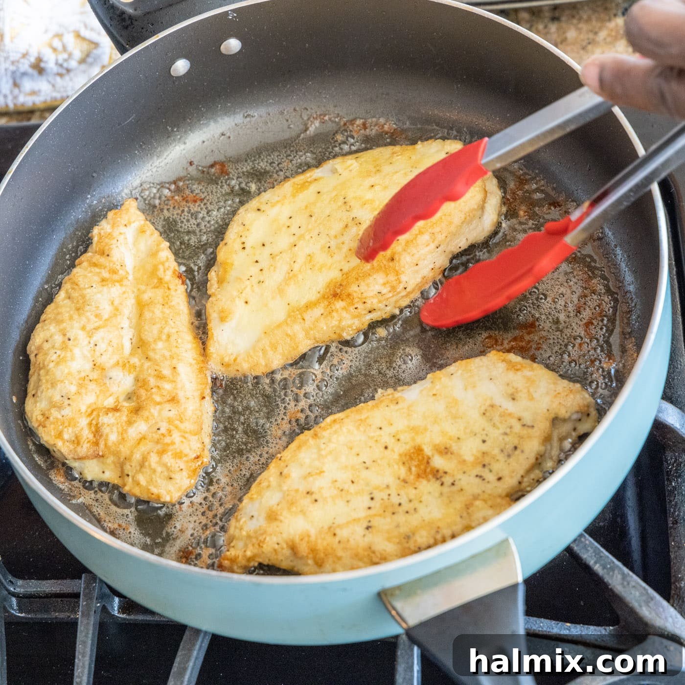 Cooking Chicken to Golden Brown Golden-brown chicken breasts cooking in a skillet, being turned with tongs