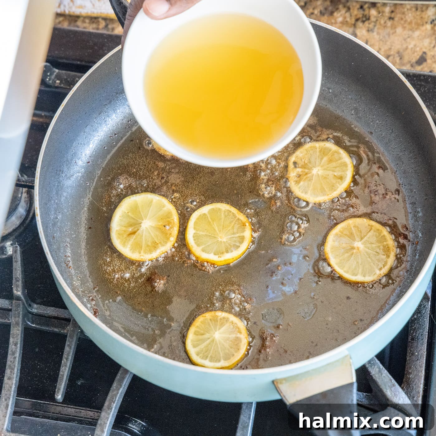 Adding Chicken Stock to Skillet Adding chicken stock to the skillet with lemon and chicken drippings