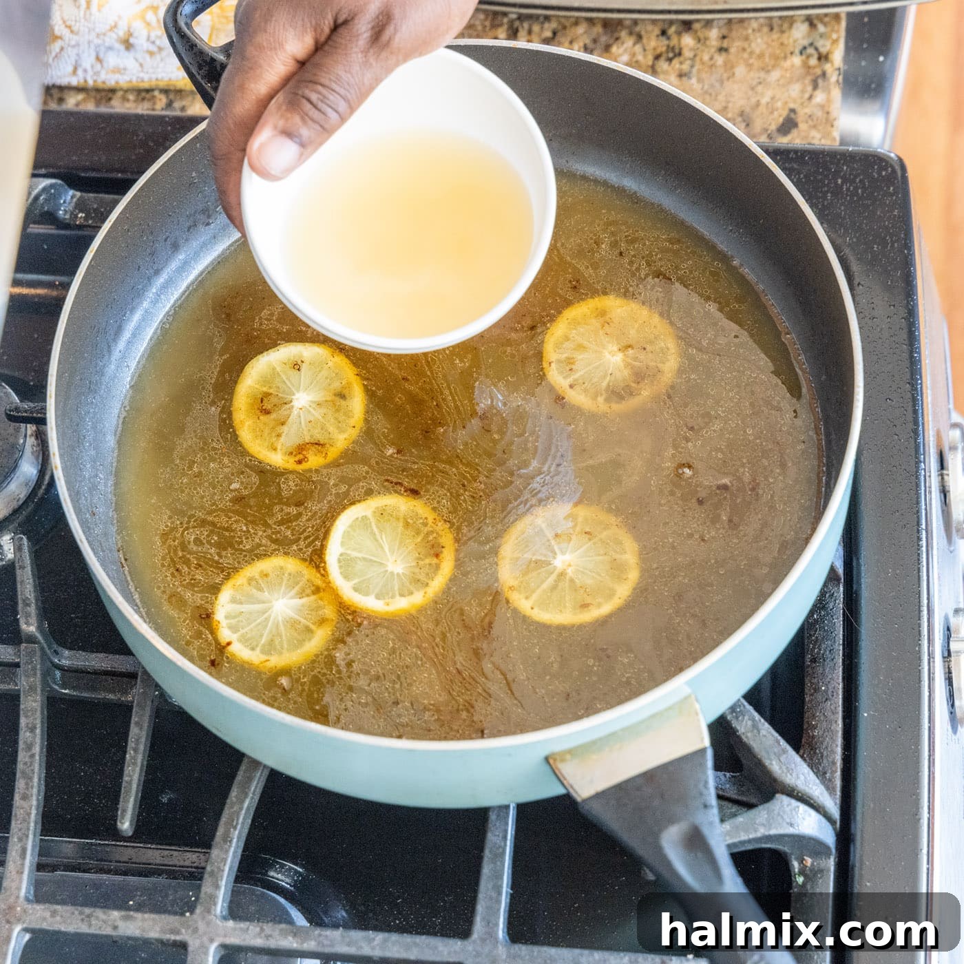 Adding White Wine to Sauce Pouring dry white wine into the simmering lemon and chicken stock mixture