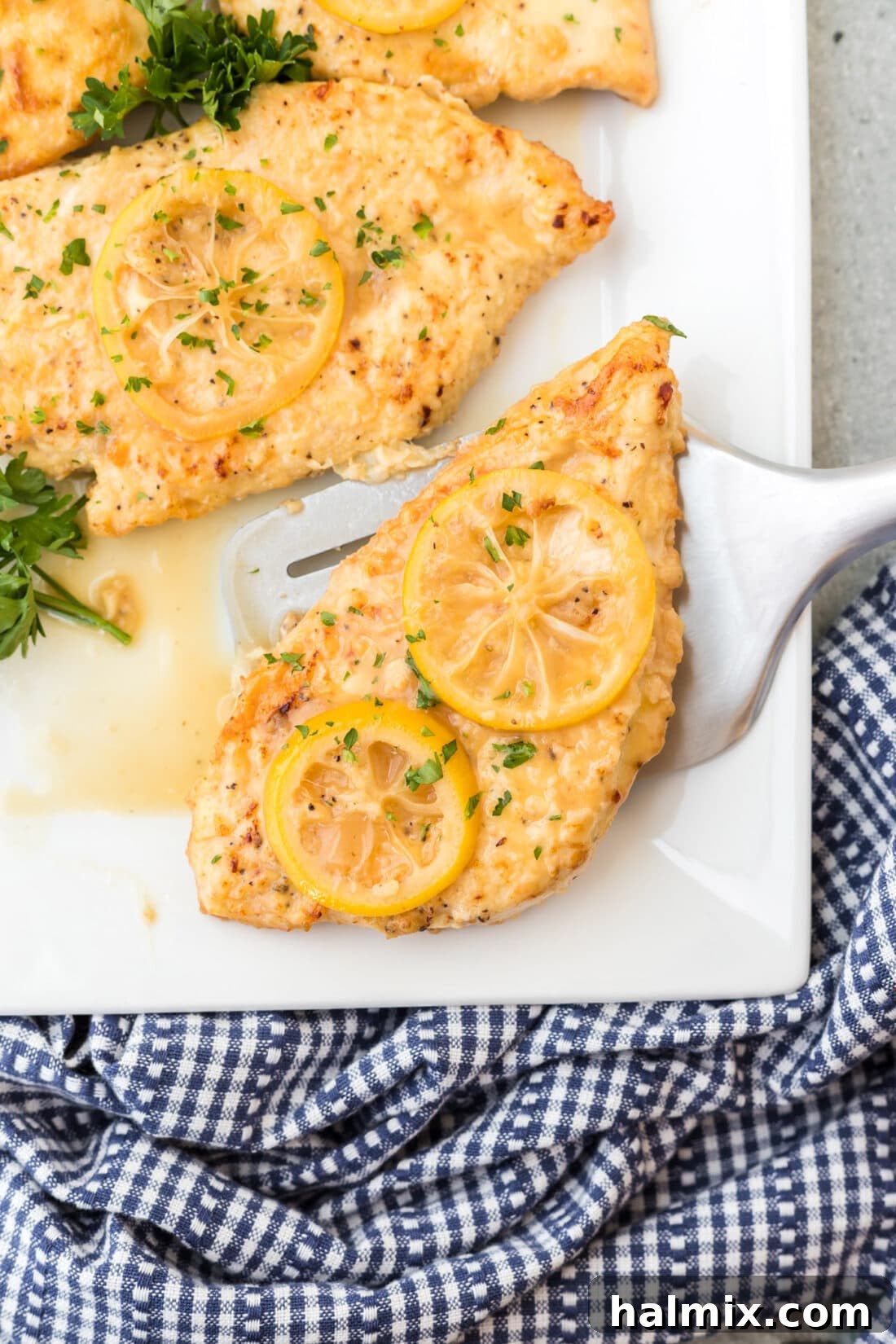 Lifting Chicken Francese with Spatula Spatula lifting a piece of Chicken Francese from the skillet, showing the tender chicken and rich sauce