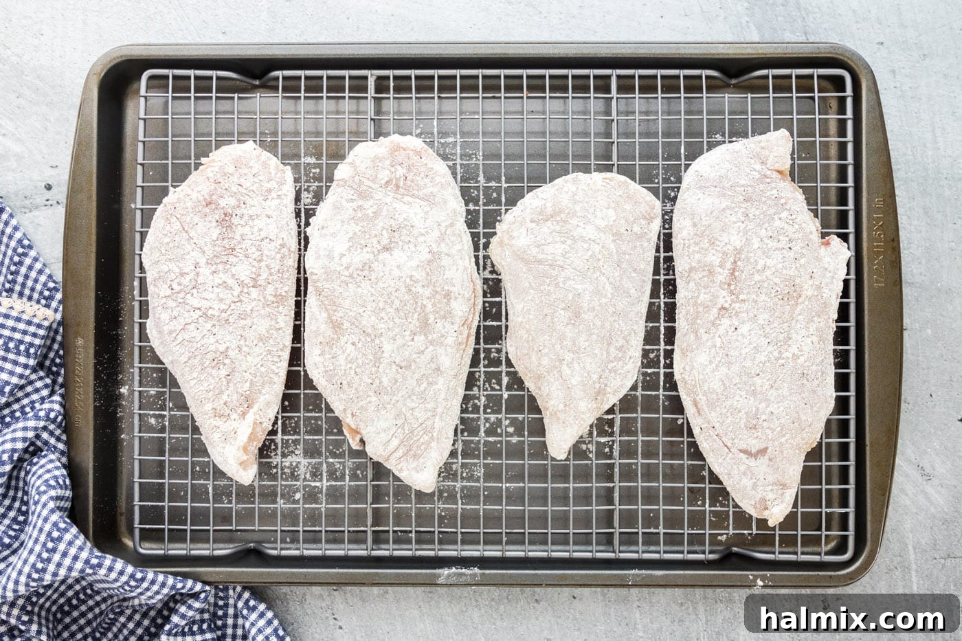 Dredging Chicken in Flour Pounded chicken breasts being dredged in the flour mixture