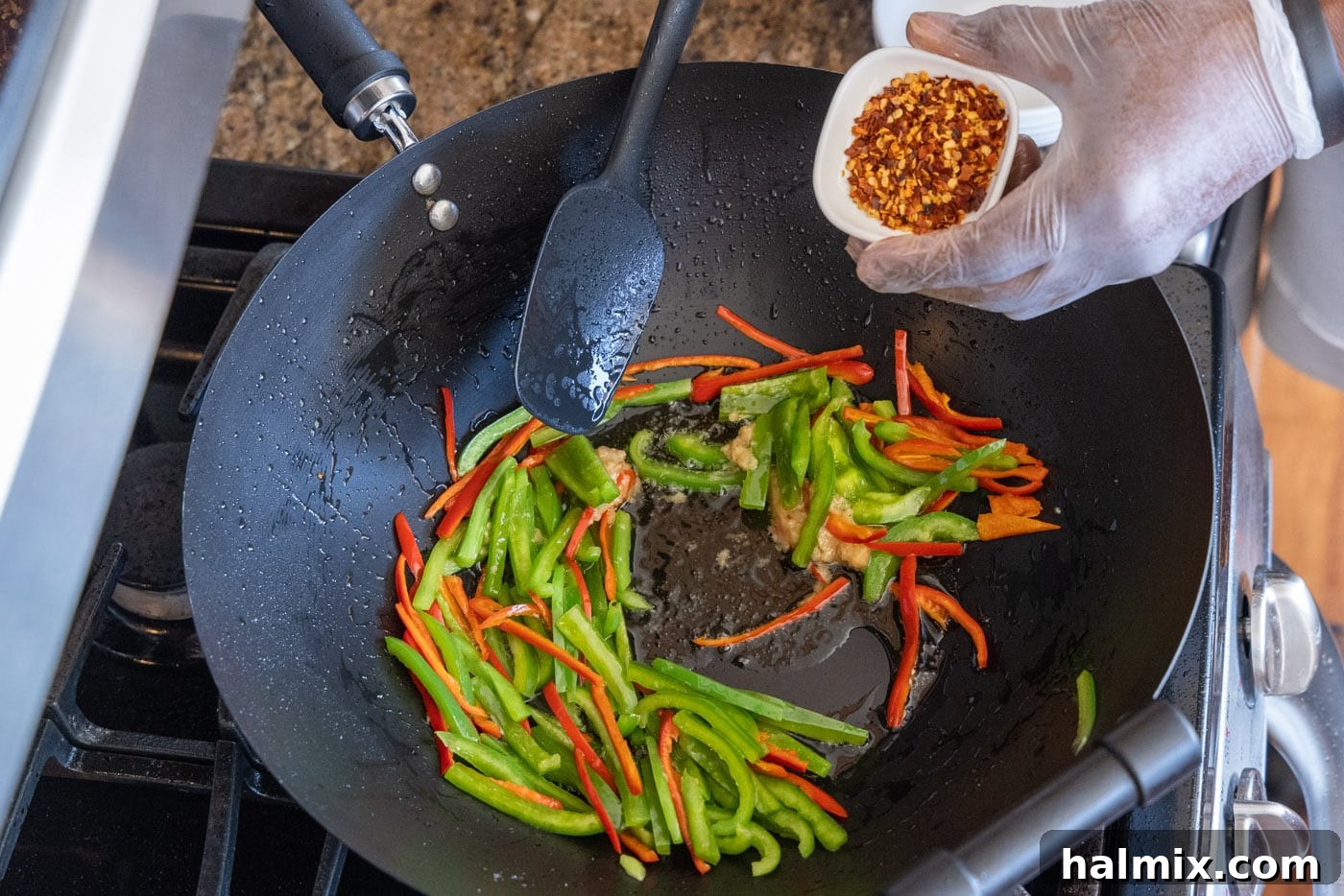 Red pepper flakes being added to the stir-fry, intensifying the spice
