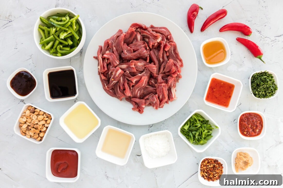 A collection of fresh ingredients laid out for Kung Pao Beef preparation, including peppers, ginger, and beef